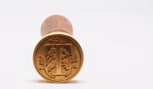 A closeup of a stamp that prints the letter T with floral patterns.